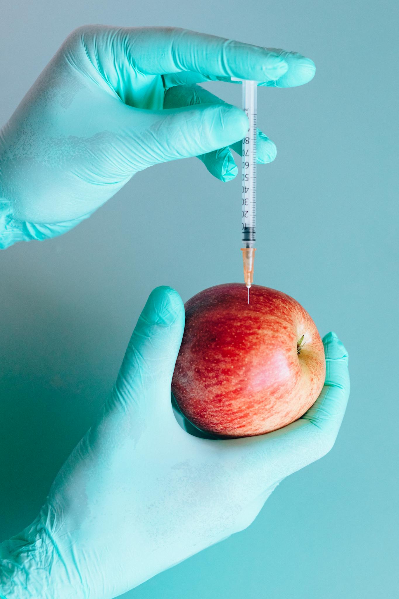Close-up of a syringe injecting an apple, illustrating genetic modification or medical concepts.